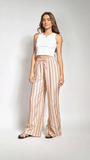 Woman wearing a white top and striped pants standing against a plain background